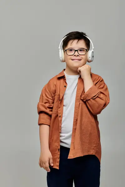 Un niño con síndrome de Down, con audífonos, posa para la cámara. - foto de stock