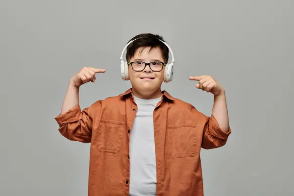 Little boy with Down syndrome wearing headphones, pointing to his ears. — Stock Photo