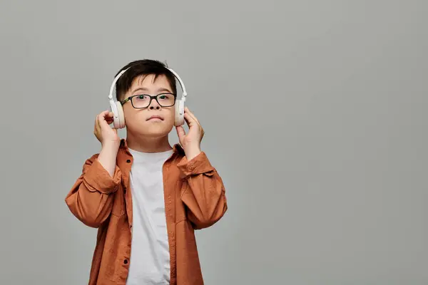 Charming boy with Down syndrome felizmente escucha música en los auriculares. - foto de stock