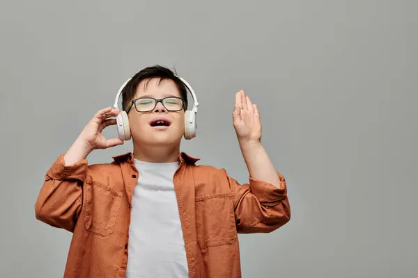 A little boy with Down syndrome joyfully listens to music through headphones. — Stock Photo