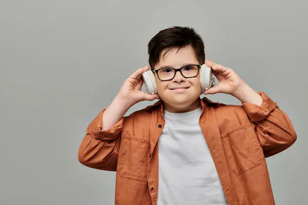 Мальчик с синдромом Дауна, в очках, слушает музыку. — стоковое фото