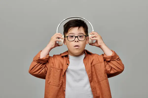 A boy with Down syndrome with glasses immerses in music through headphones. — Stock Photo