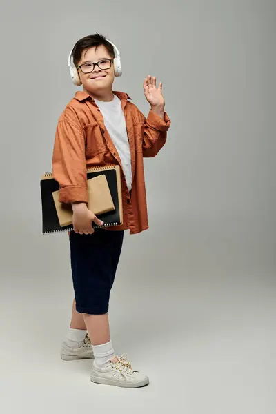 Little boy with Down syndrome wearing headphones, holding books. — Stock Photo