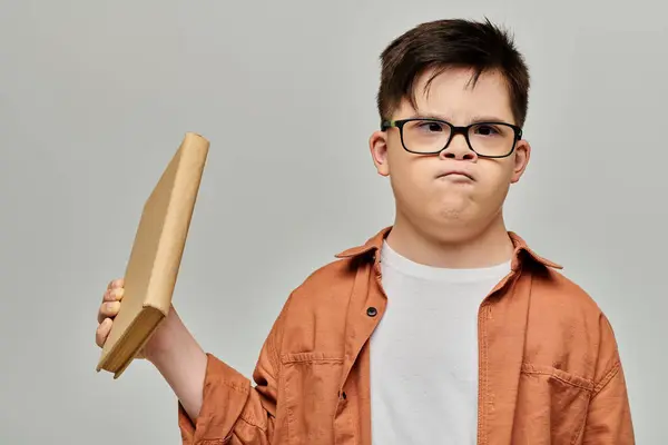 Little boy with Down syndrome with glasses engrossed in a book. — Stock Photo