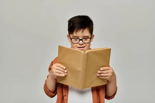 Petit garçon avec trisomie 21 avec des lunettes lire intensément — Photo de stock