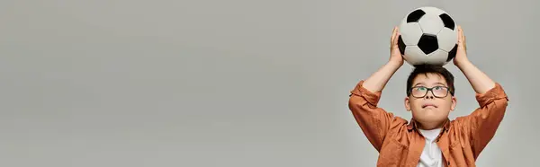 Little boy with Down syndrome joyfully holds soccer ball above his head. — Stock Photo