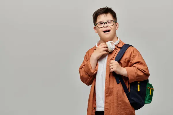 Un niño con síndrome de Down con gafas y una mochila. — Stock Photo