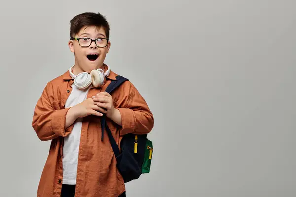 A little boy with Down syndrome with glasses and a backpack explores with curiosity. — Stock Photo