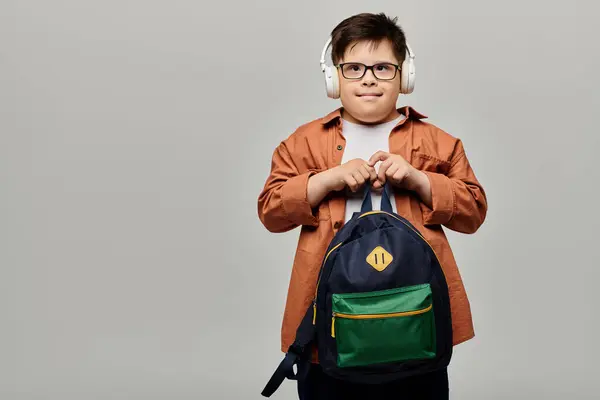 Kleiner Junge mit Down-Syndrom trägt Kopfhörer und einen Rucksack. — Stockfoto