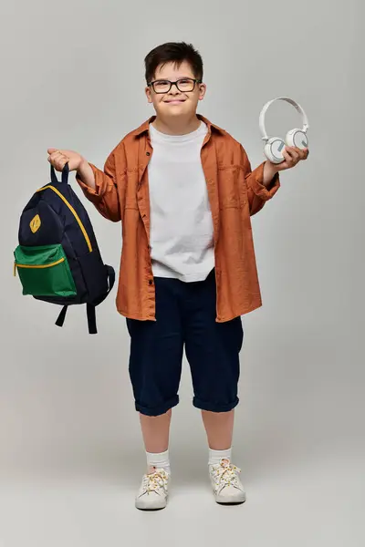 Little boy with Down syndrome with backpack and headphones. — Stock Photo