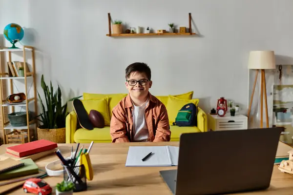 A adorable boy with Down syndrome engrossed in using a laptop at his desk. — Stock Photo