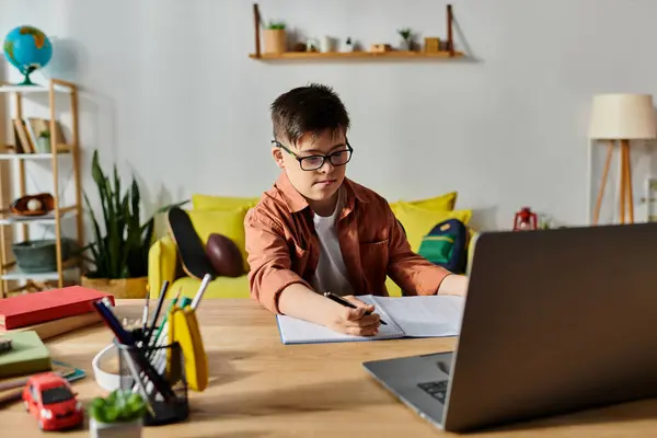 Un adorable garçon avec le syndrome de Down concentré sur son ordinateur portable à la maison. — Photo de stock