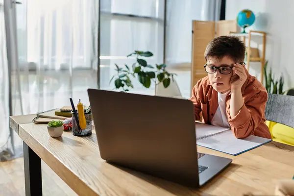 A boy with Down syndrome with a laptop, deeply focused at his desk — Stock Photo