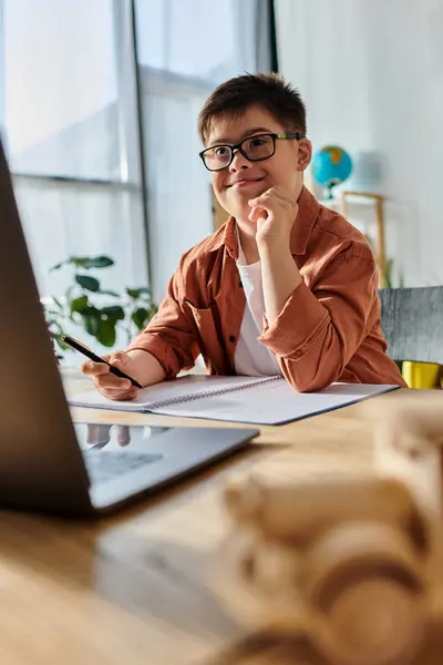 Adorable boy with Down syndrome in glasses studying with laptop at desk — Stock Photo