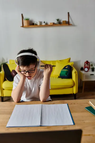 Boy with Down syndrome wearing headphones, writing in notebook at home. — Stock Photo