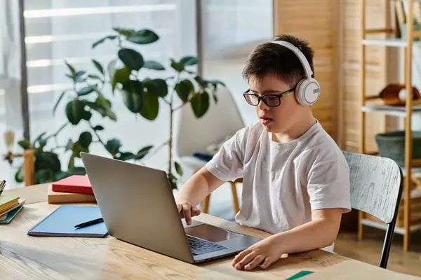 Мальчик с синдромом Дауна использует ноутбук дома в наушниках. — стоковое фото