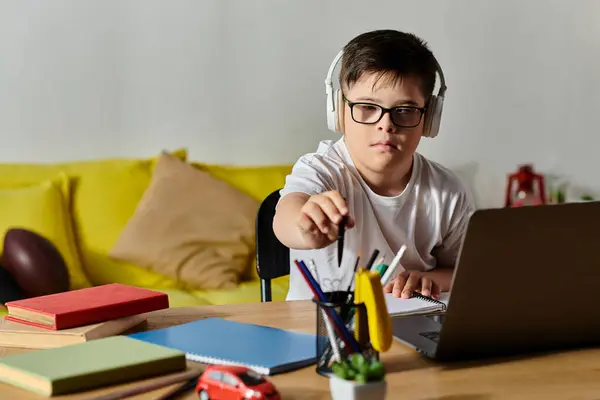Adorable garçon avec le syndrome de Down assis à un bureau, interagissant avec un ordinateur portable. — Photo de stock
