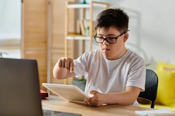 Menino com síndrome de Down usando computador tablet, usando óculos. — Fotografia de Stock