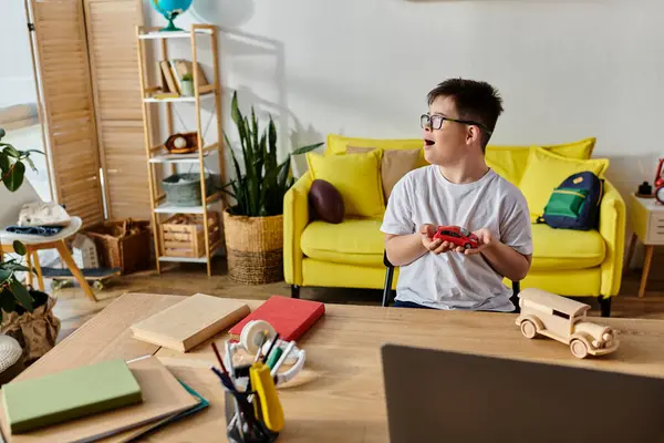 Little boy with Down syndrome at desk, plays with toys and explores laptop. — Stock Photo