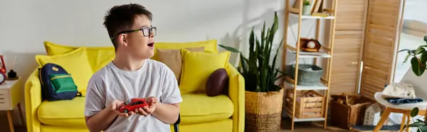 Adorable boy with Down syndrome immersed in a game with toy in cozy living room. — Stock Photo