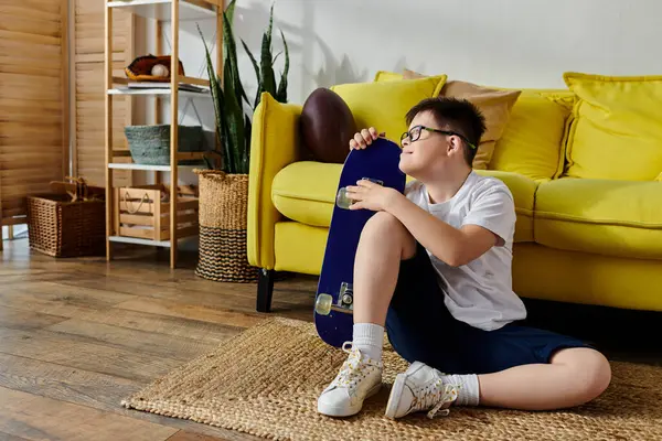 Entzückender Junge mit Down-Syndrom mit Skateboard auf dem Boden in einem gemütlichen Raum sitzend. — Stockfoto