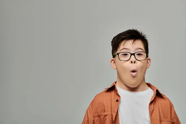 Un niño pequeño con síndrome de Down hace una expresión tonta. - foto de stock