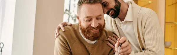 Двоє чоловіків, щаслива гомосексуальна пара, поділяють теплі обійми у своїй сучасній вітальні, наповненій любов'ю та сміхом. — стокове фото
