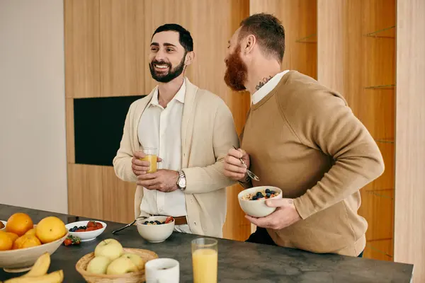 Dos hombres felices, una pareja gay, están sentados en una cocina moderna, desayunando y compartiendo un momento de amor y conexión. - foto de stock