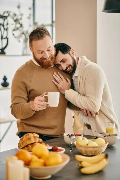 Dos hombres comparten un cálido abrazo en la cocina de un apartamento moderno, expresando su amor y felicidad en los brazos del otro. - foto de stock