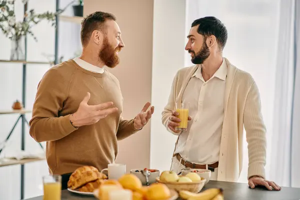 Two men engaged in conversation at a modern kitchen table in a cozy apartment setting. — Stock Photo