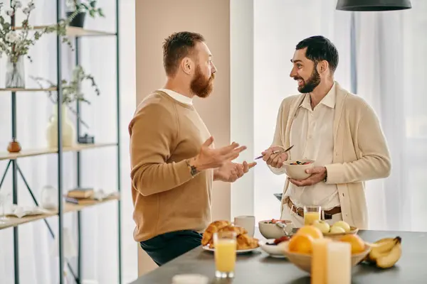 Dos hombres gay felices charlando en una cocina moderna, discutiendo opciones de desayuno y disfrutando de la compañía de los demás. - foto de stock