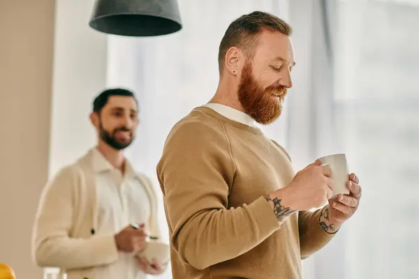 Una coppia gay felice in piedi davanti a una tazza di caffè, che condivide un momento d'amore in un appartamento moderno. — Foto stock