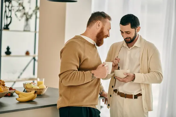 Deux hommes, un couple gay heureux, debout dans une cuisine moderne, engagés dans une conversation animée. — Photo de stock