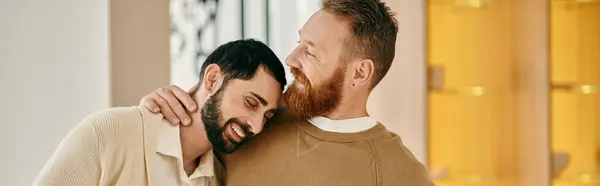 Two men hug each other warmly, expressing love and affection in front of a vibrant yellow wall. — Stock Photo