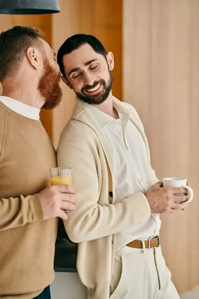 Zwei Männer plaudern fröhlich und schlürfen Kaffee in der gemütlichen Küche einer modernen Wohnung. — Stockfoto