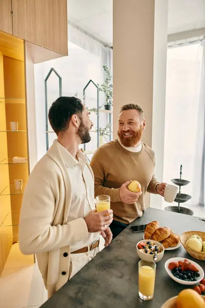 Two men enjoying a loving moment in the kitchen, surrounded by food and drinks. — Stock Photo