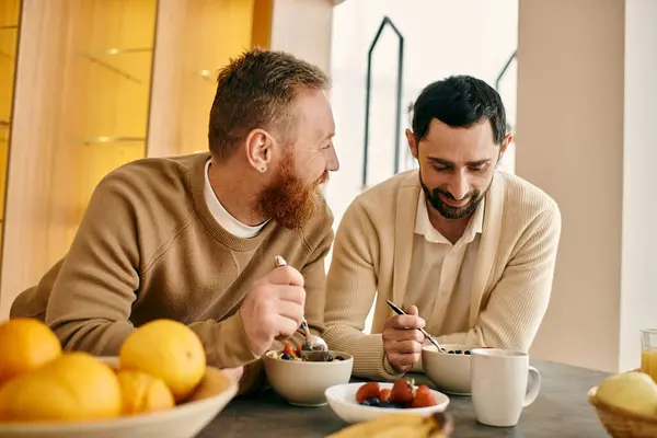 Two men, a happy gay couple, are enjoying a cozy breakfast together in their modern apartment. — Stock Photo