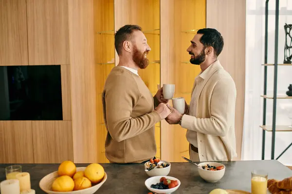 Two men, a happy gay couple, are chatting over coffee in a modern kitchen. — Stock Photo