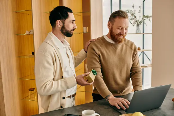 Zwei Männer, ein glückliches homosexuelles Paar, versunken in ihrem Laptop in einer modernen Küche, genießen die gemeinsame Zeit. — Stockfoto