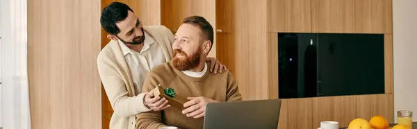 Two men happily working on a laptop together in a stylish kitchen, enjoying quality time cooking and bonding. — Stock Photo