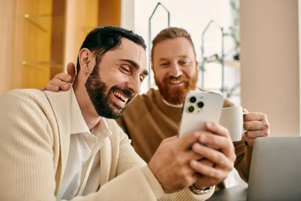 Two men sitting at a table, engrossed in smartphone, sharing a moment of modern connection and togetherness. — Stock Photo