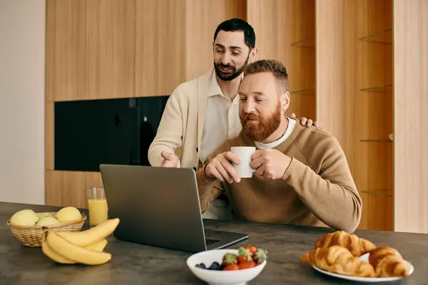 A man and a woman sit at a table, engrossed in a laptop screen, their expressions reflecting shared interest and affection. — Stock Photo