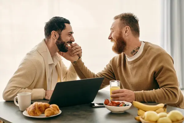 A joyful gay couple engaged in deep conversation while seated at a table in a cozy modern apartment. — Stock Photo