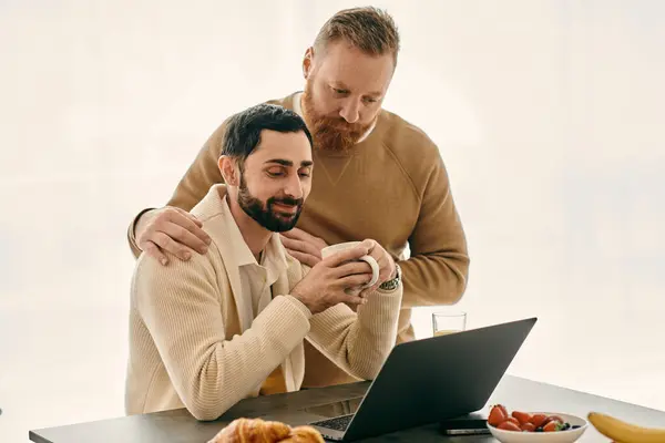 Two men enjoying a moment of togetherness, working on a laptop at a table in a comfortable setting. — Stock Photo