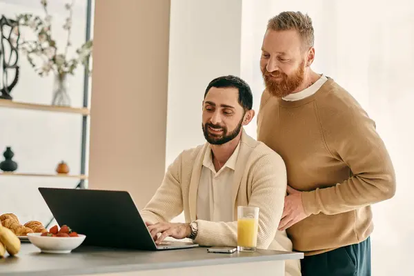 Zwei Männer programmieren auf einem Laptop in einer modernen Küche und arbeiten in einer harmonischen Atmosphäre zusammen.. — Stockfoto