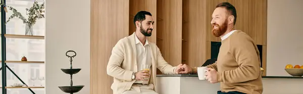 Two men engaged in a lively discussion while seated in a modern kitchen, enjoying each others company. — Stock Photo