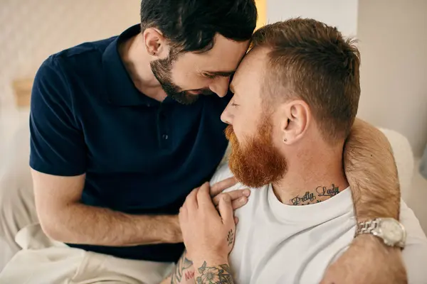 Two men, a happy gay couple, embracing each other on a couch in a modern living room. — Stock Photo