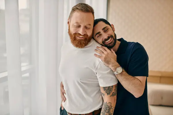 Deux hommes s'embrassent chaleureusement devant une fenêtre dans un salon moderne, mettant en valeur leur amour et leur connexion. — Photo de stock