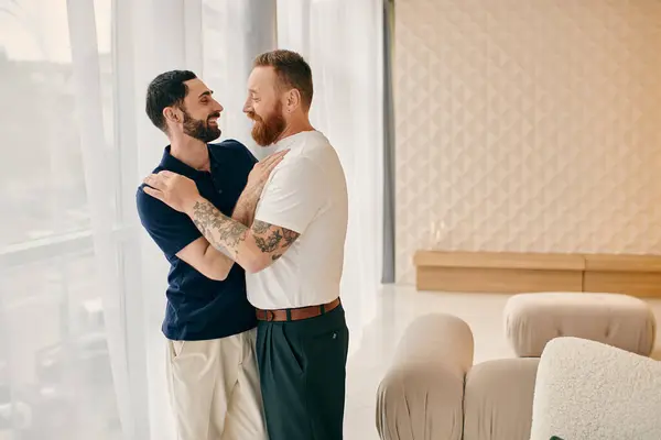 Щаслива гей пара обіймається в сучасній вітальні, одягненій в повсякденний одяг, насолоджуючись якісним часом разом. — стокове фото