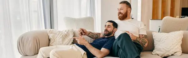 A gay couple in casual clothes sitting on a couch in a modern living room. — Stock Photo
